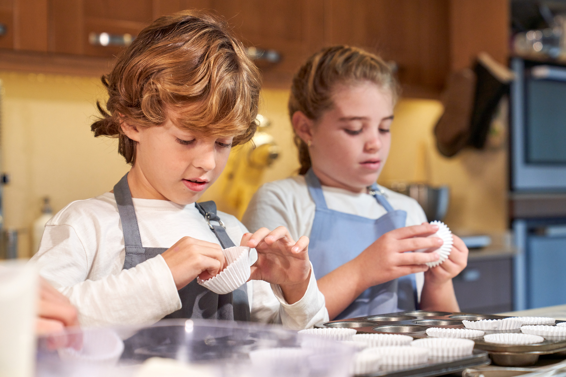 Attentive kids cooking preparing baking pan for cupcakes